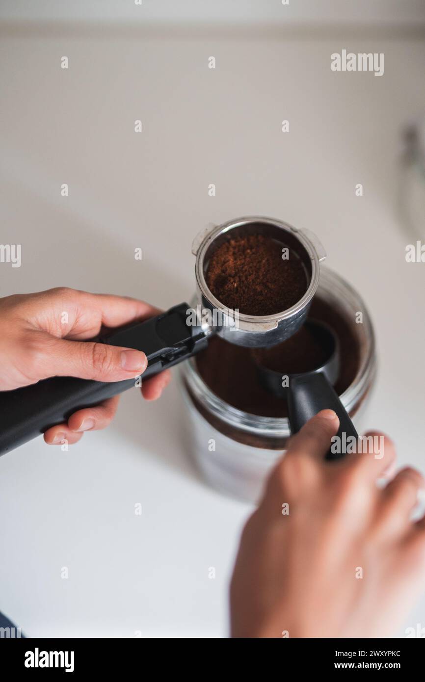 Primo piano delle mani per preparare un portafiltro con caffè appena macinato Foto Stock