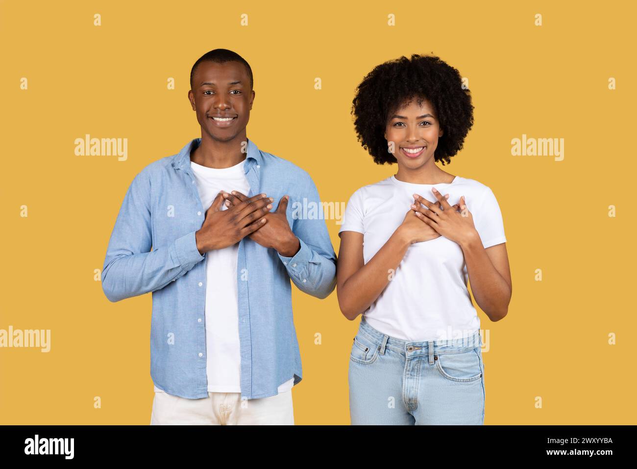 Due persone con le mani sul cuore in giallo Foto Stock