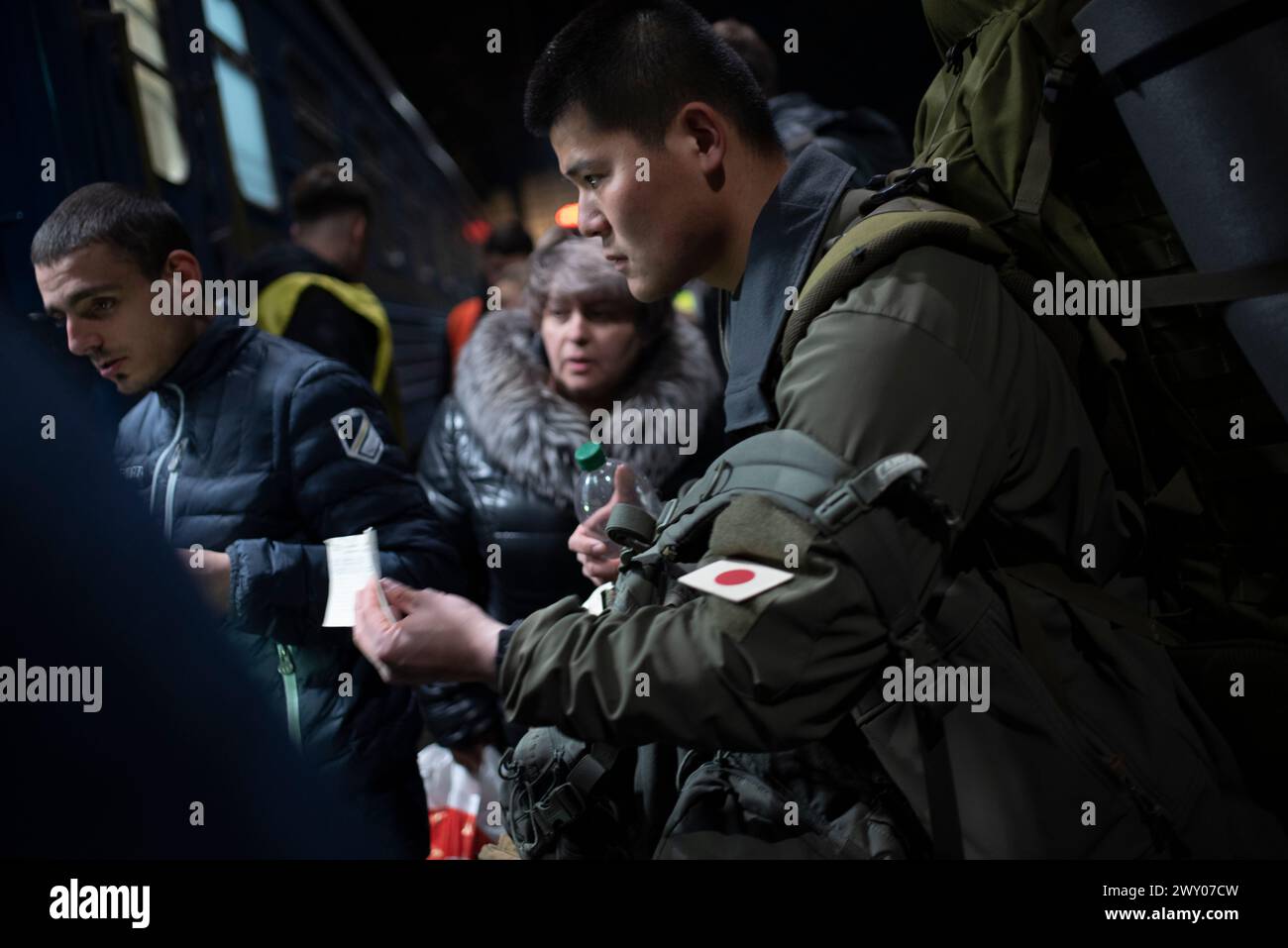 Un soldato giapponese, che vuole unirsi all'esercito ucraino, mostra il suo biglietto per il treno che lo porterà vicino al suo campo militare. Foto Stock