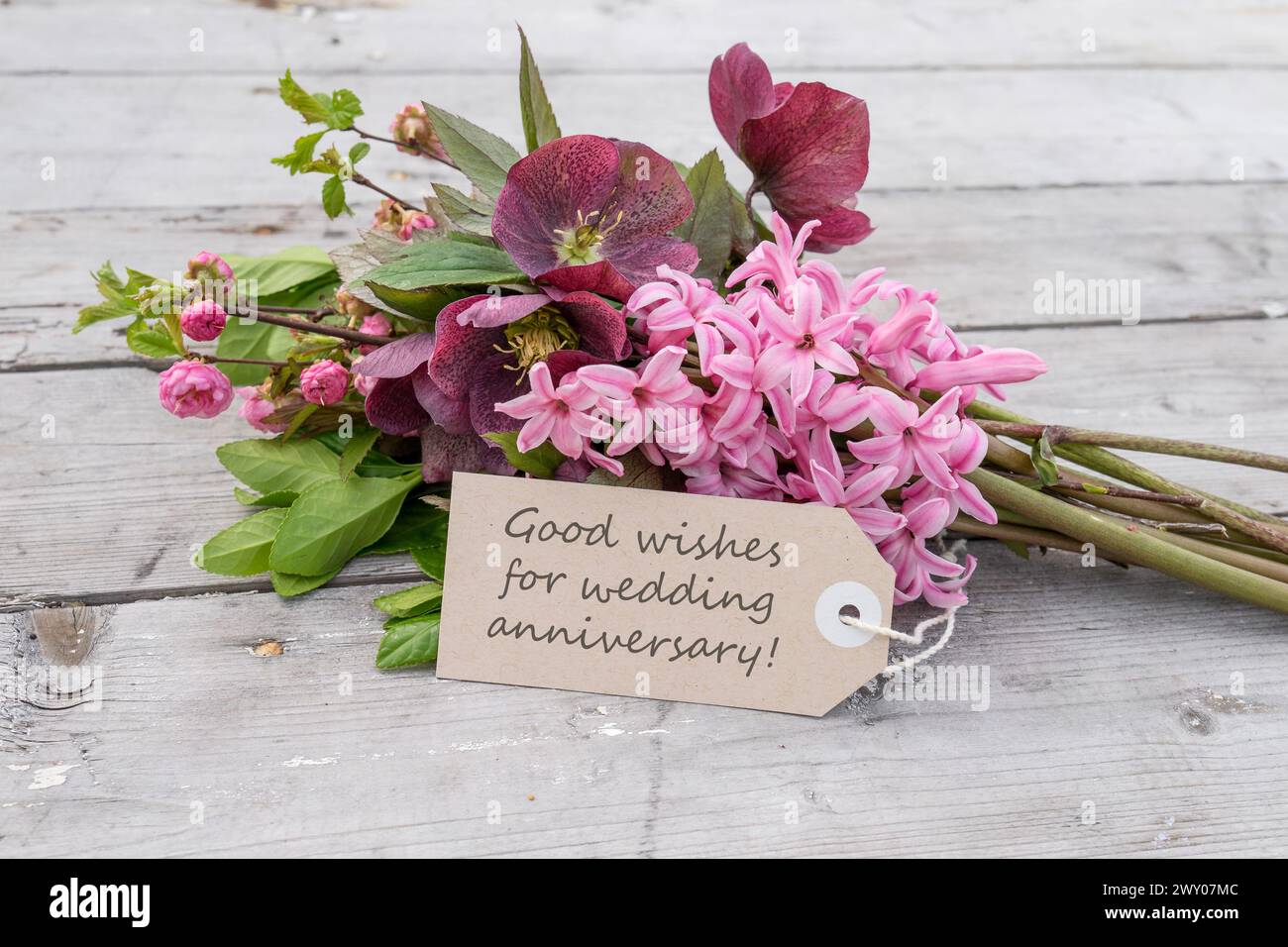 Bouquet con giacinti rosa, rose di Natale e cartolina con testo inglese: Auguri per l'anniversario di matrimonio Foto Stock