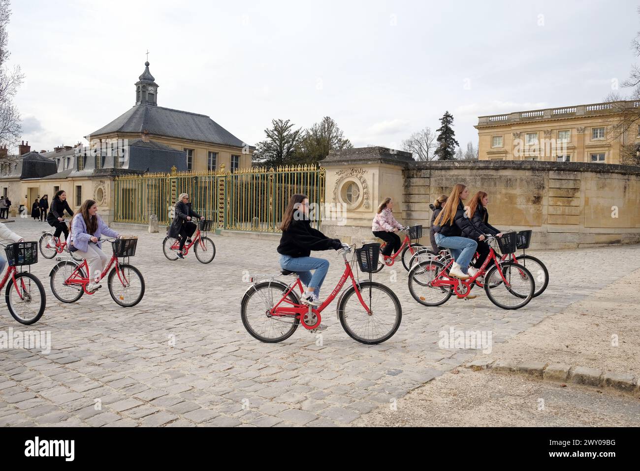 VERSAILLES, FRANCIA - 8 marzo 2024. Turisti in bicicletta durante il tour dell'imponente Reggia di Versailles, del castello francese e del monumento storico. Foto Stock
