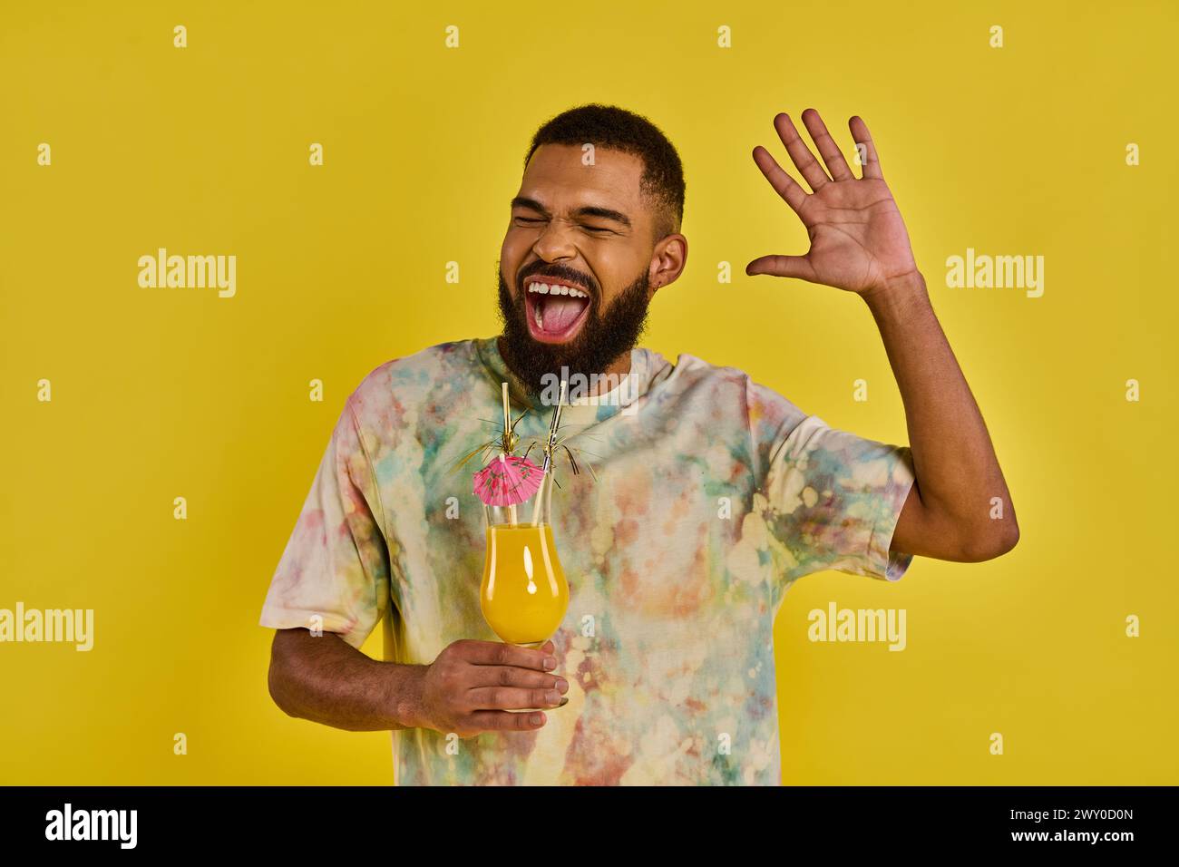 Un uomo con una barba rigogliosa che afferra una bottiglia di succo vibrante, trasuda un'aria di raffinatezza e divertimento. Foto Stock