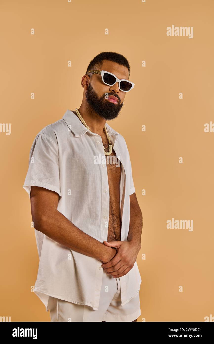 Un uomo con barba trasuda un look cool con occhiali da sole e una camicia elegante, che incarna fascino e fiducia nel suo aspetto. Foto Stock