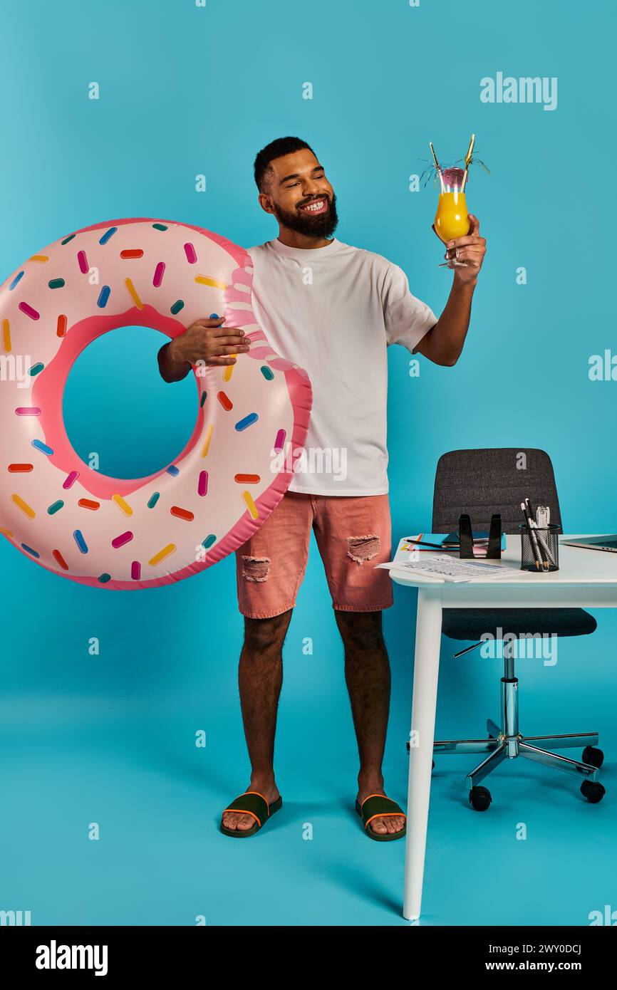 Un uomo tiene con gioia in mano un drink e una ciambella massiccia, godendo chiaramente delle sue prelibatezze. Foto Stock