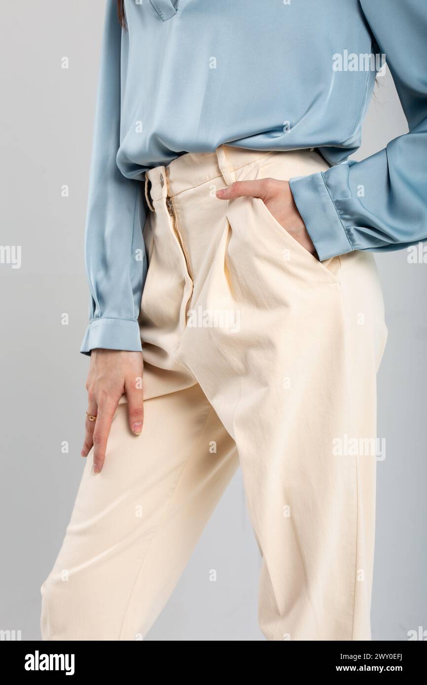 Modello alla moda in pantaloni beige e blusa blu con tasca a mano su sfondo isolato. Adatto per gli annunci di moda. Foto Stock