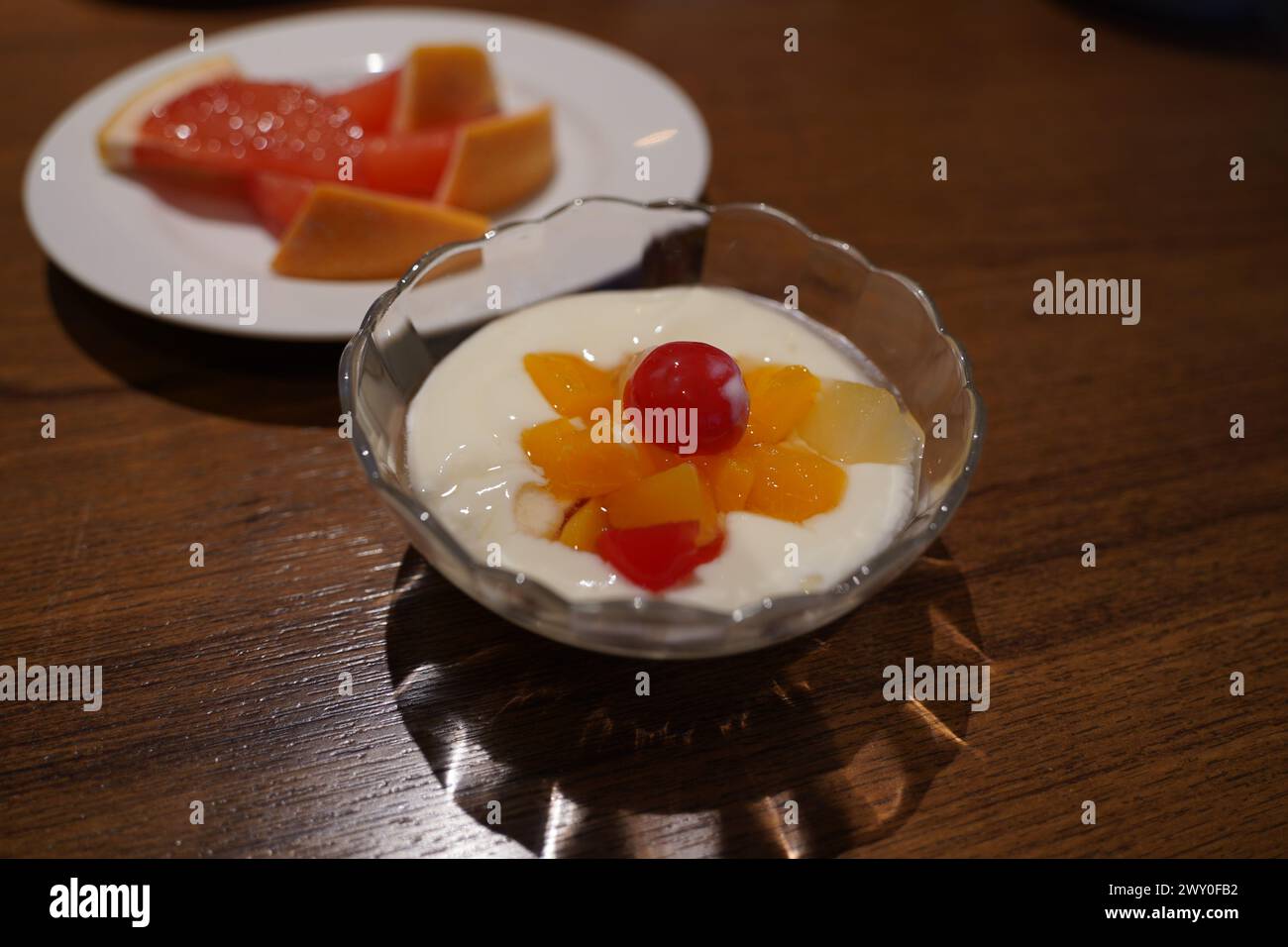 Yogurt con frutta in un recipiente di vetro su un tavolo di legno Foto Stock