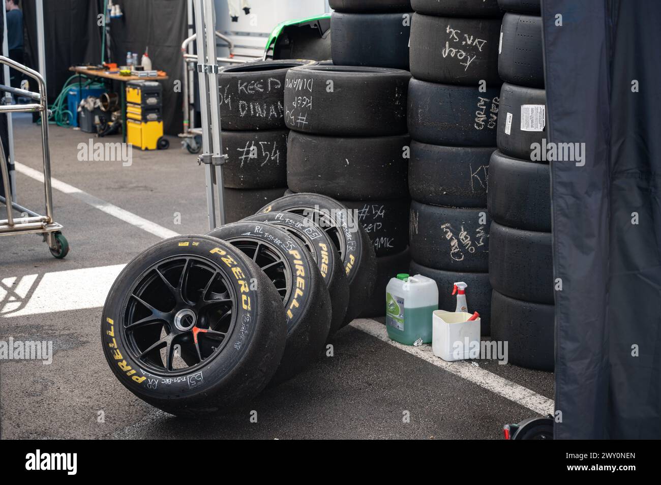 Dettaglio delle pile di pneumatici Pirelli PZero slick. contrassegnato con note con gesso bianco e una bottiglia d'acqua con una cabina per pulirli Foto Stock