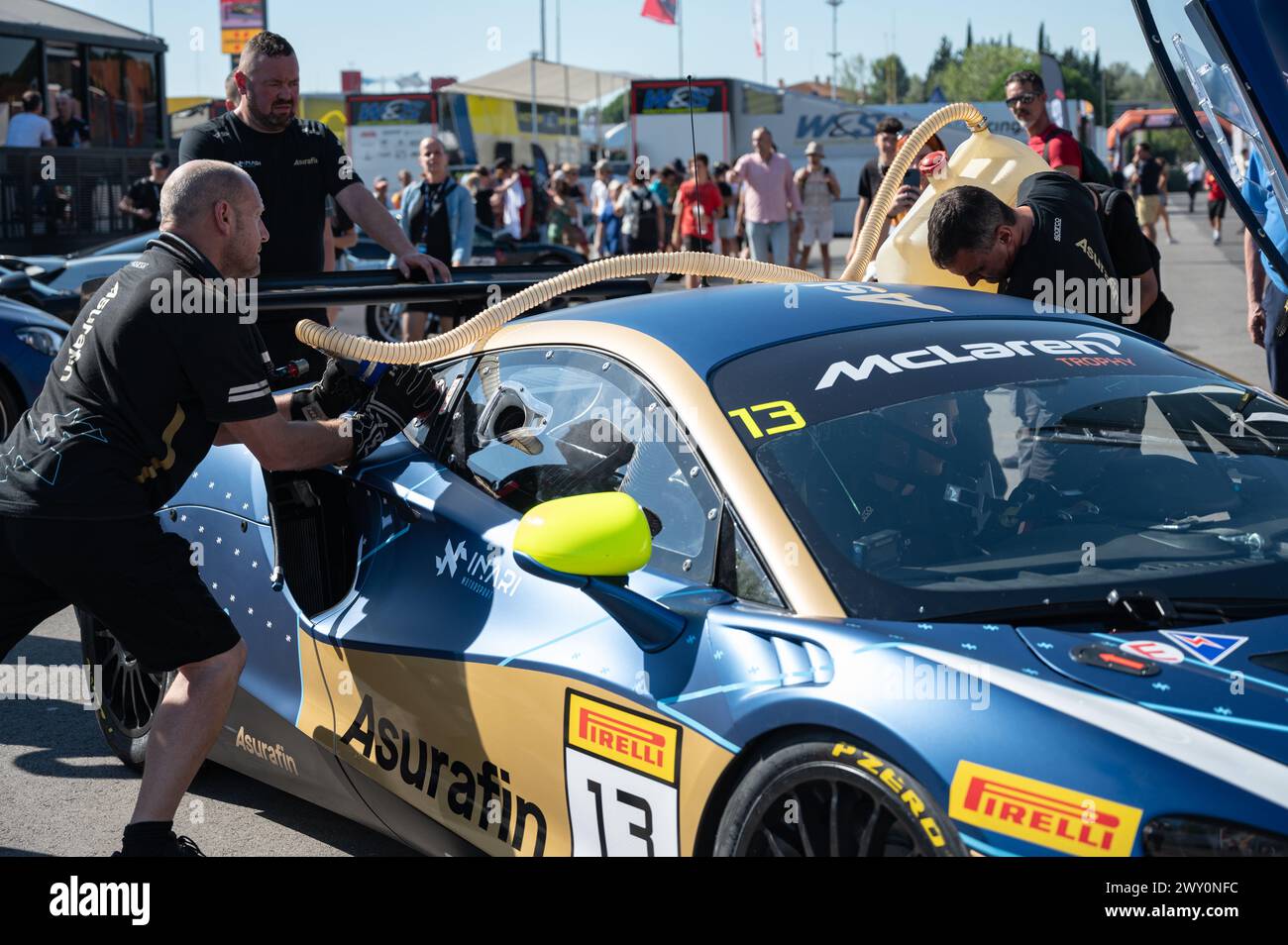 Meccanici che riforniscono l'auto da corsa McLaren Artura Trophy Europe, un meccanico trasporta il tubo e l'altra tanica di carburante a caricamento rapido Foto Stock