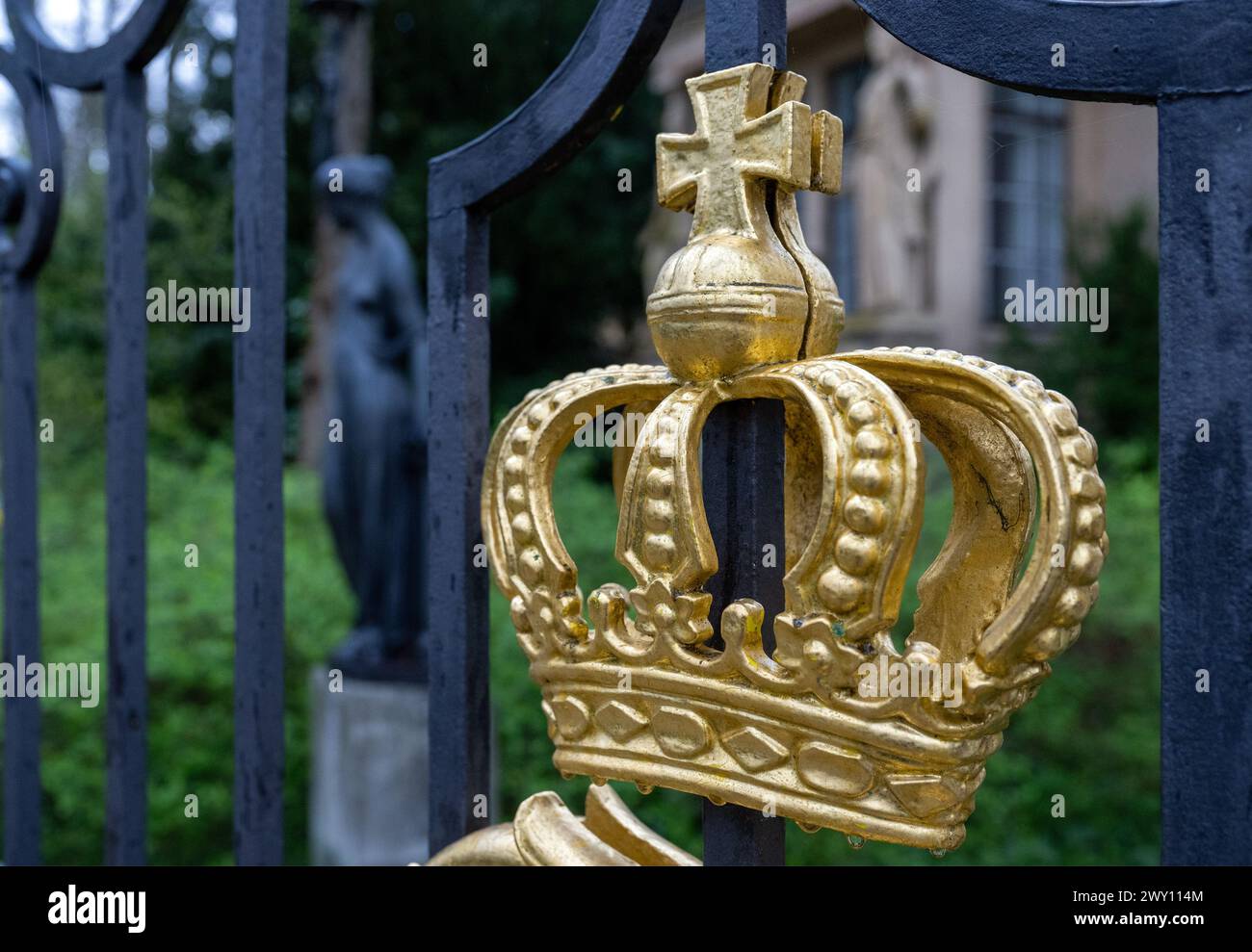 Potsdam, Germania. 3 aprile 2024. Un cancello d'ingresso con una corona dorata e la piccola portineria del Palazzo Glienicke, che fa parte della Fondazione dei Palazzi e dei Giardini prussiani Berlino-Brandeburgo (SPSG). Nel corso della tradizionale conferenza stampa annuale del 5 aprile 2024, il bilancio dell'anno passato e i piani della fondazione saranno presentati. Credito: Soeren Stache/dpa/Alamy Live News Foto Stock