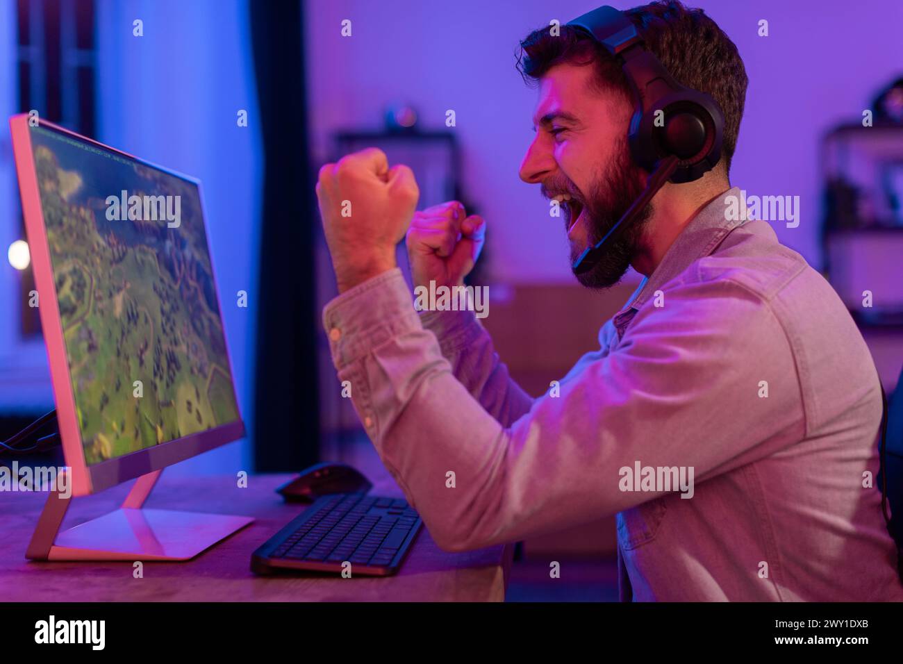 Uomo frustrato allo schermo del computer, festeggiando la vittoria Foto Stock
