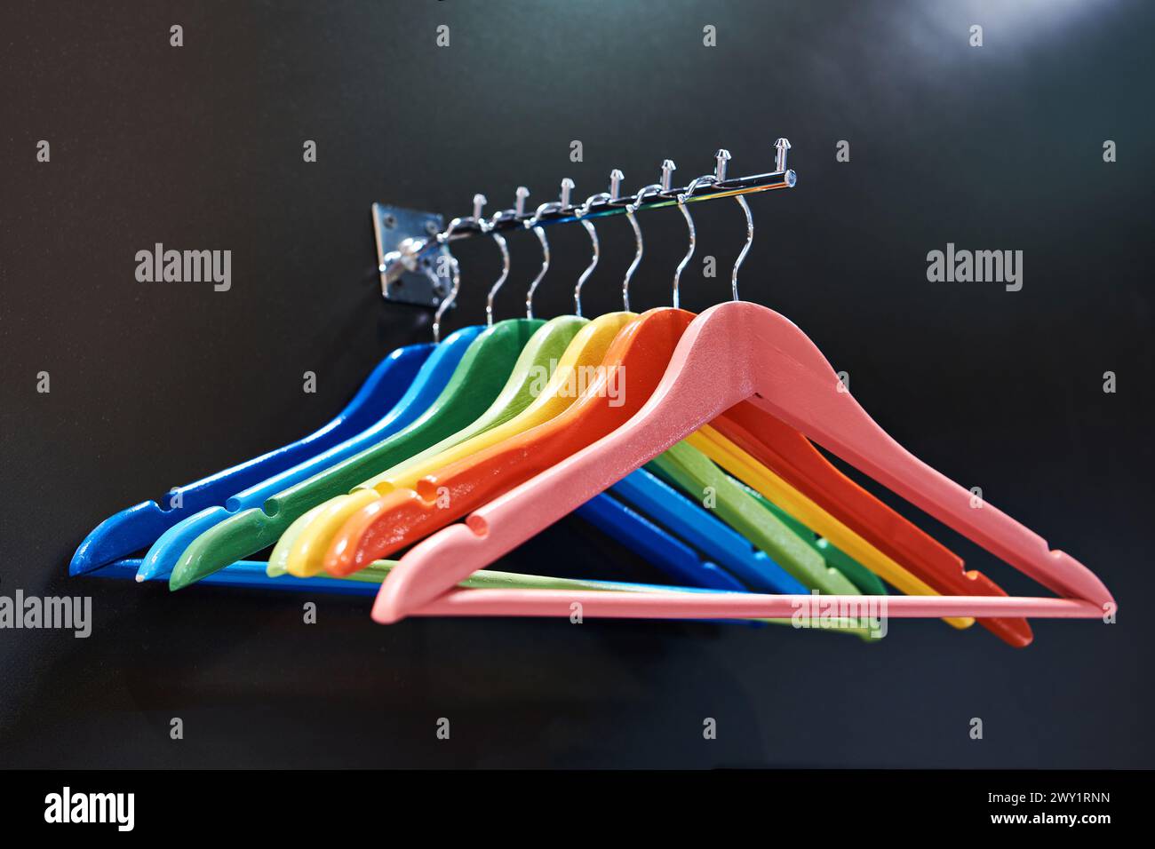 Appendiabiti colorati sulla barra appendiabiti del negozio Foto Stock