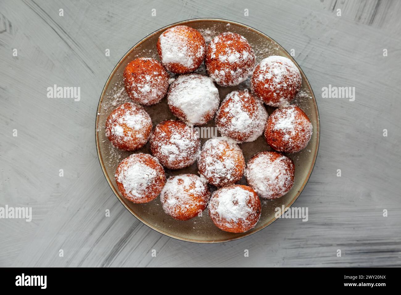 Ciambelle fritte fatte in casa con zucchero a velo su un piatto, vista dall'alto. Foto Stock