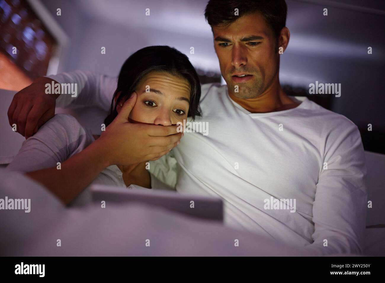 Coppia, tablet e film spaventosi di notte, guardare e riprodurre film online in streaming su app o sito Web di casa. Persone, intrattenimento e relax in abbraccio Foto Stock