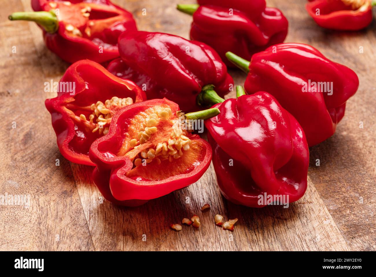 Peperoni habanero rossi e metà di pepe su fondo di legno. Foto Stock