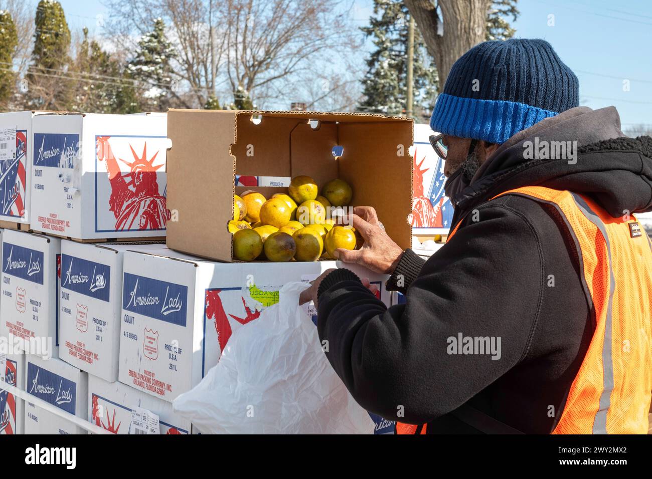 Detroit, Michigan - il cibo gratuito viene distribuito alle persone che partecipano a una fiera della salute della comunità. Un lavoratore confeziona arance per la distribuzione. Foto Stock