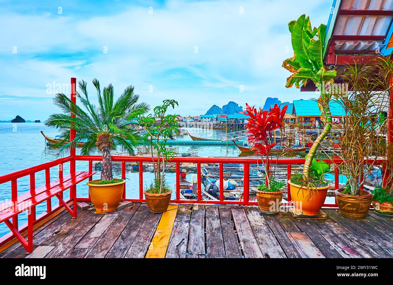 La vecchia terrazza in legno della palafitta, decorata con piante in vasi contro il porto con barche da pesca, il villaggio di Ko Panyi e l'Ao Phang Nga National Foto Stock