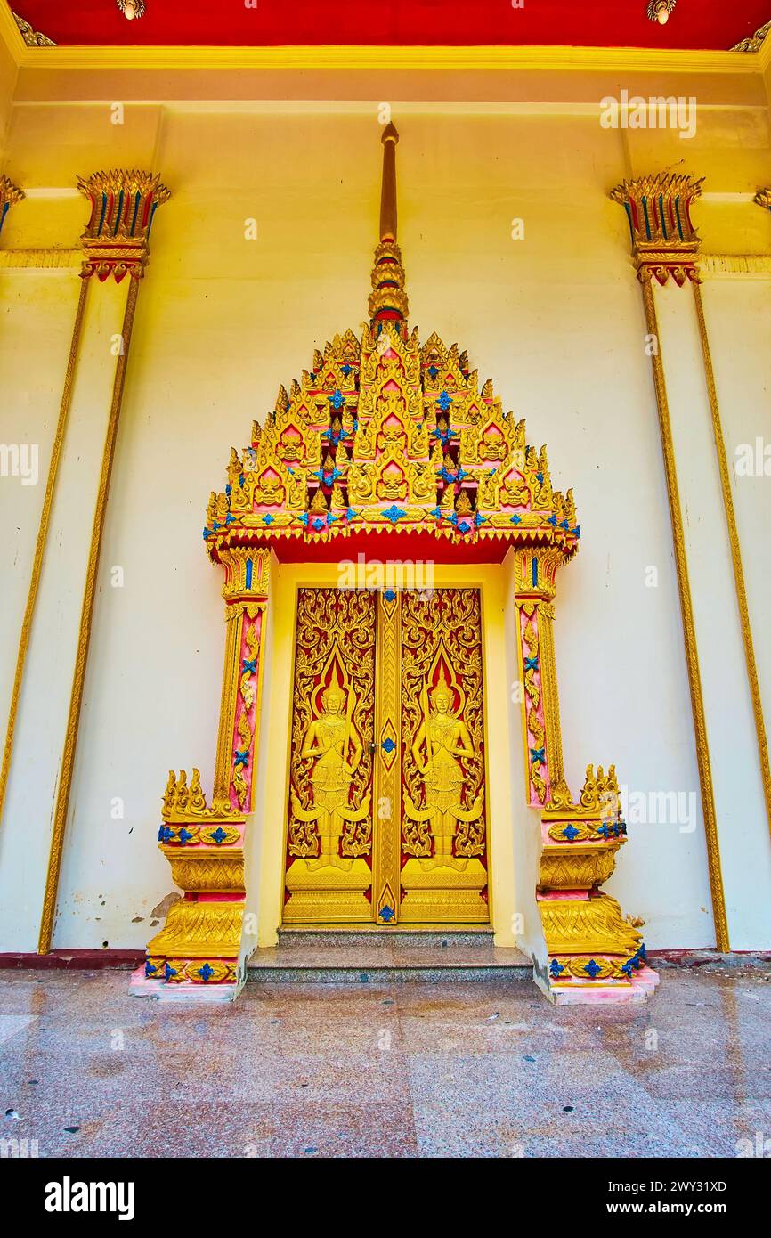 La porta a forma di guglia scolpita dell'Ubosot del Tempio di Wat Suwan Kuha e la porta, decorata con figure devata (divinità), Phang Nga, Thailandese Foto Stock