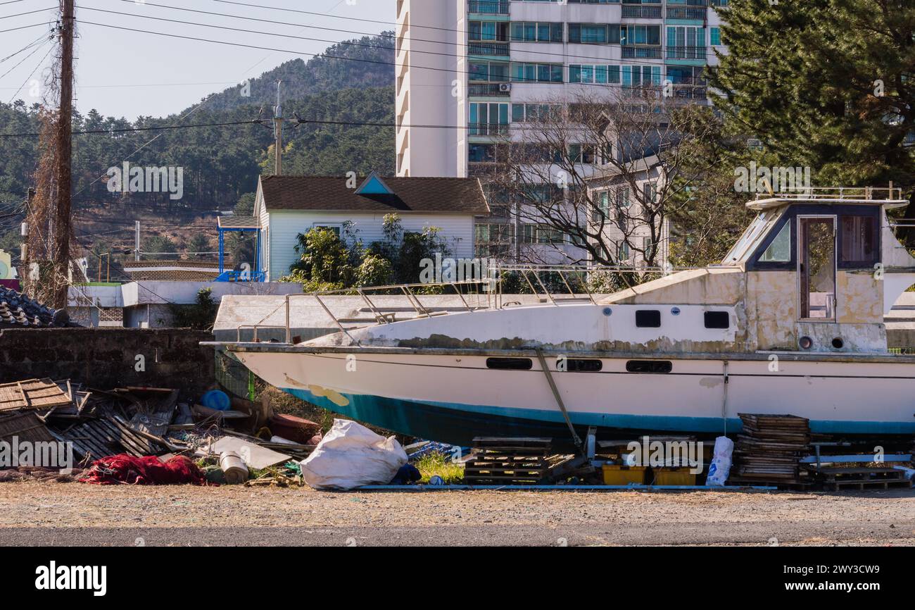 Grande imbarcazione in stato di abbandono nel bacino di carenaggio con edifici e alberi sullo sfondo in Corea del Sud Foto Stock