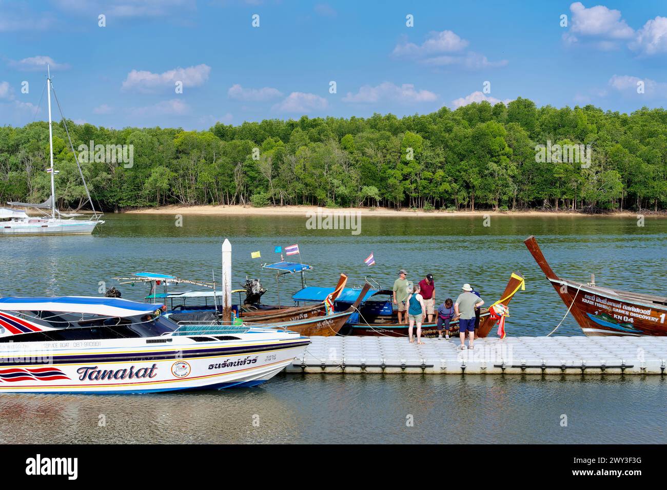 Turisti in un molo vicino al fiume Krabi nella città di Krabi, Thailandia, a bordo di una barca per un'escursione sul fiume, altre barche turistiche ancorate al molo Foto Stock