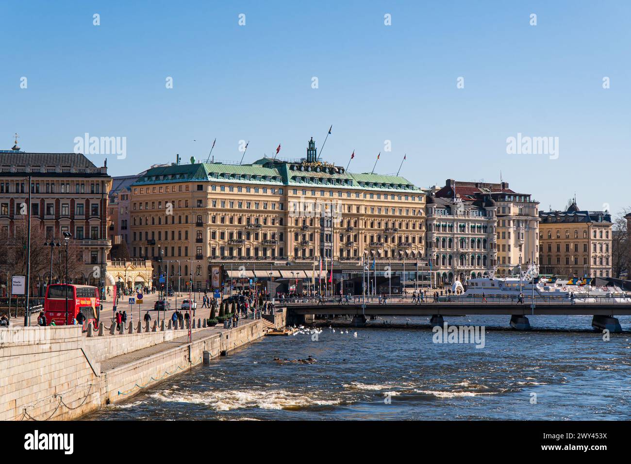 La città vecchia di Stoccolma e il centro di stoccolma. Il Grand hotel, bandiere svedesi, ponte Strömbron. Luce solare intensa, primavera. Cielo blu. Foto Stock