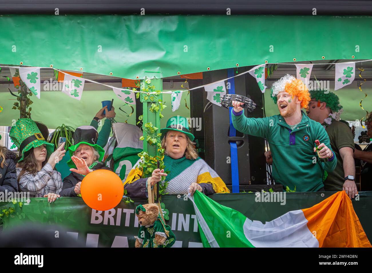 Le persone ridono e cantano su un galleggiante partecipando alla processione del giorno di San Patrizio a Londra. Giorno di San Patrizio. Foto Stock
