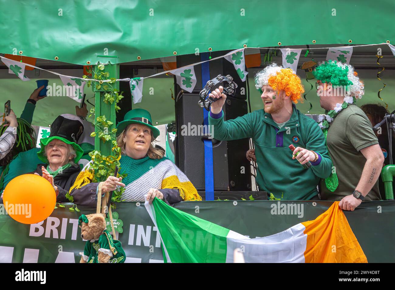 Le persone ridono e cantano su un galleggiante partecipando alla processione del giorno di San Patrizio a Londra. Giorno di San Patrizio. Foto Stock