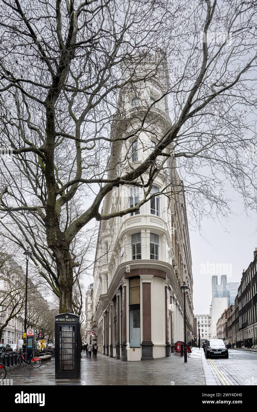 Un edificio in stile piatto di ferro nel cuore di Londra. Di fronte all'edificio, una vecchia cabina telefonica BT è stata trasformata in un hub digitale che offre Wi-Fi. Foto Stock