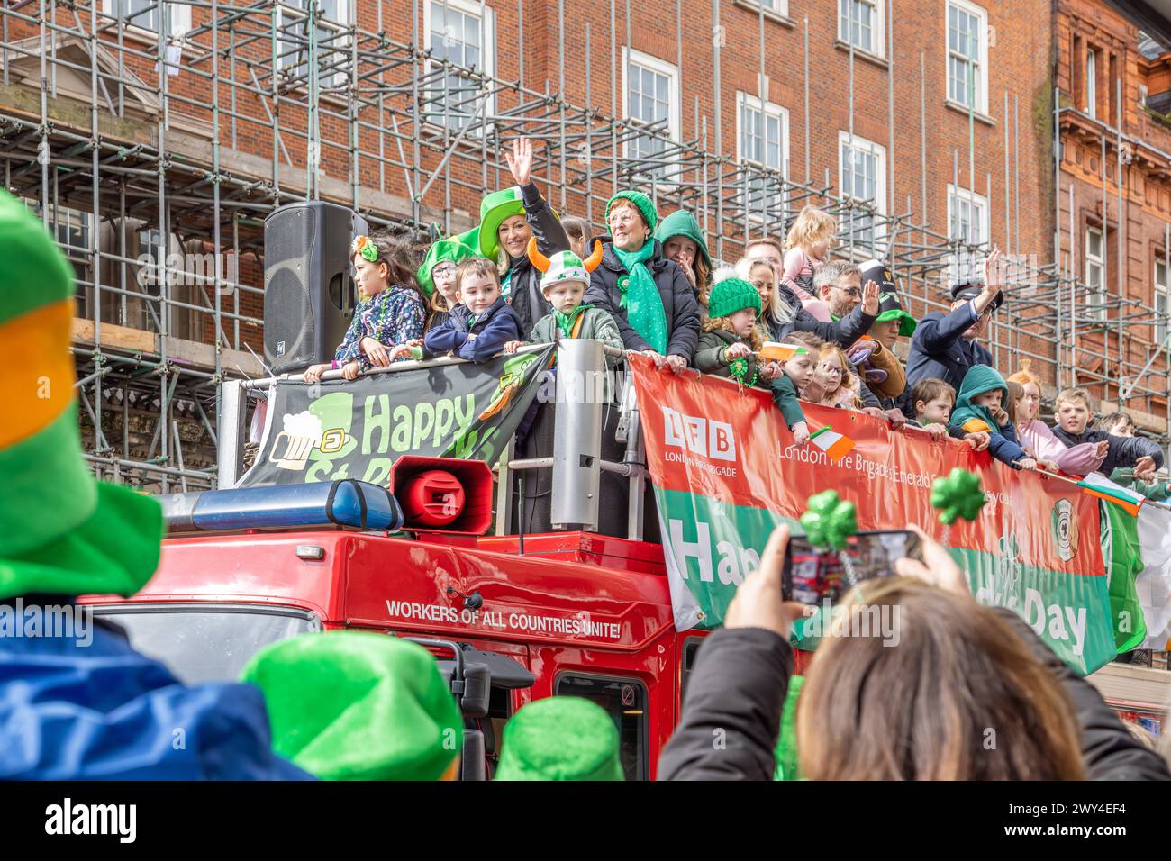 La London Fire Brigades Emerald Society passa davanti alla folla su un motore antincendio durante la processione durante le celebrazioni della parata di San Patrizio a Londra. Foto Stock