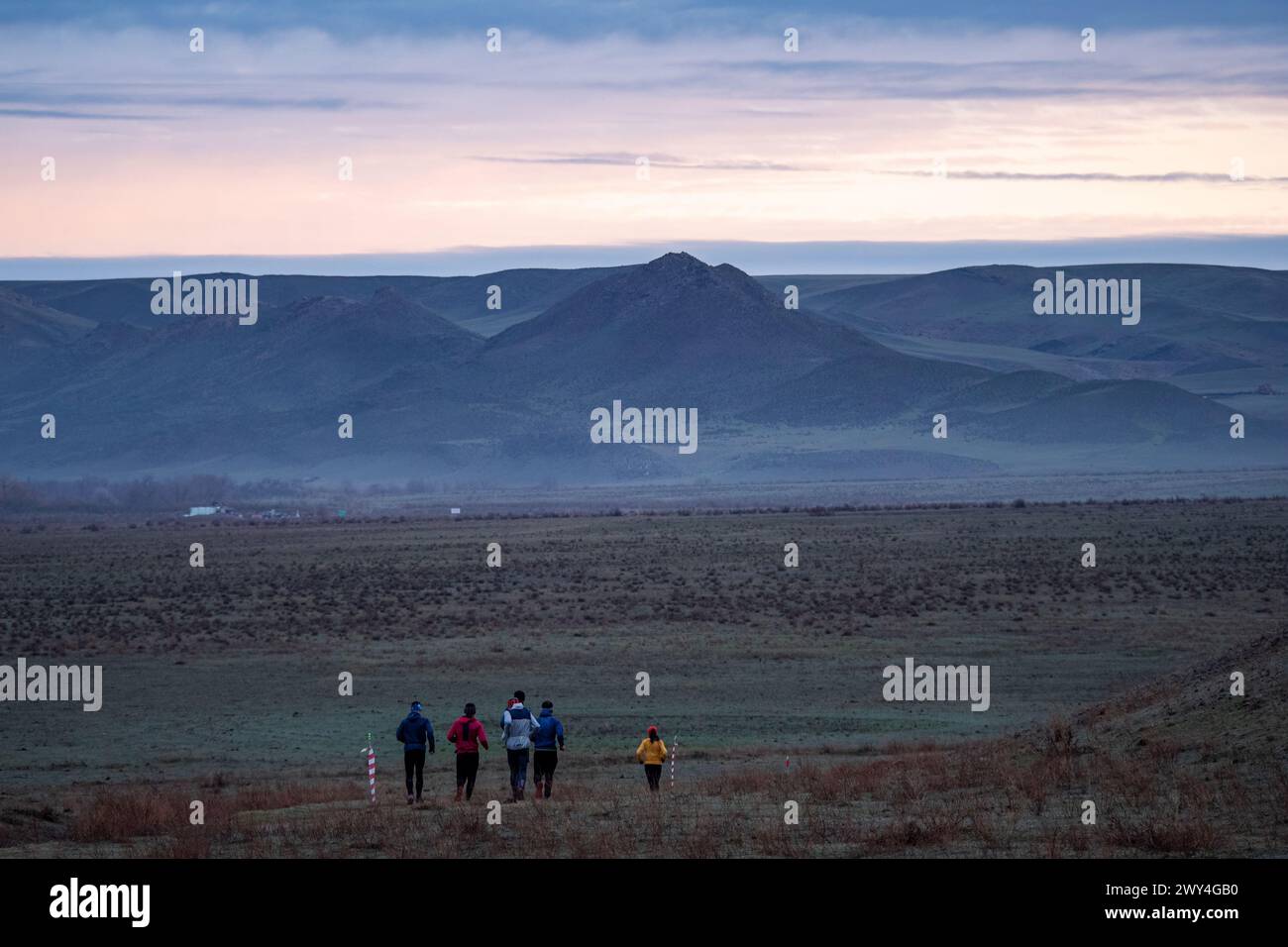 Un gruppo di atleti che corrono lungo un sentiero in una valle di montagna. All'inizio della primavera, tempo coperto, pittoresco paesaggio circostante. Sport all'aperto Foto Stock