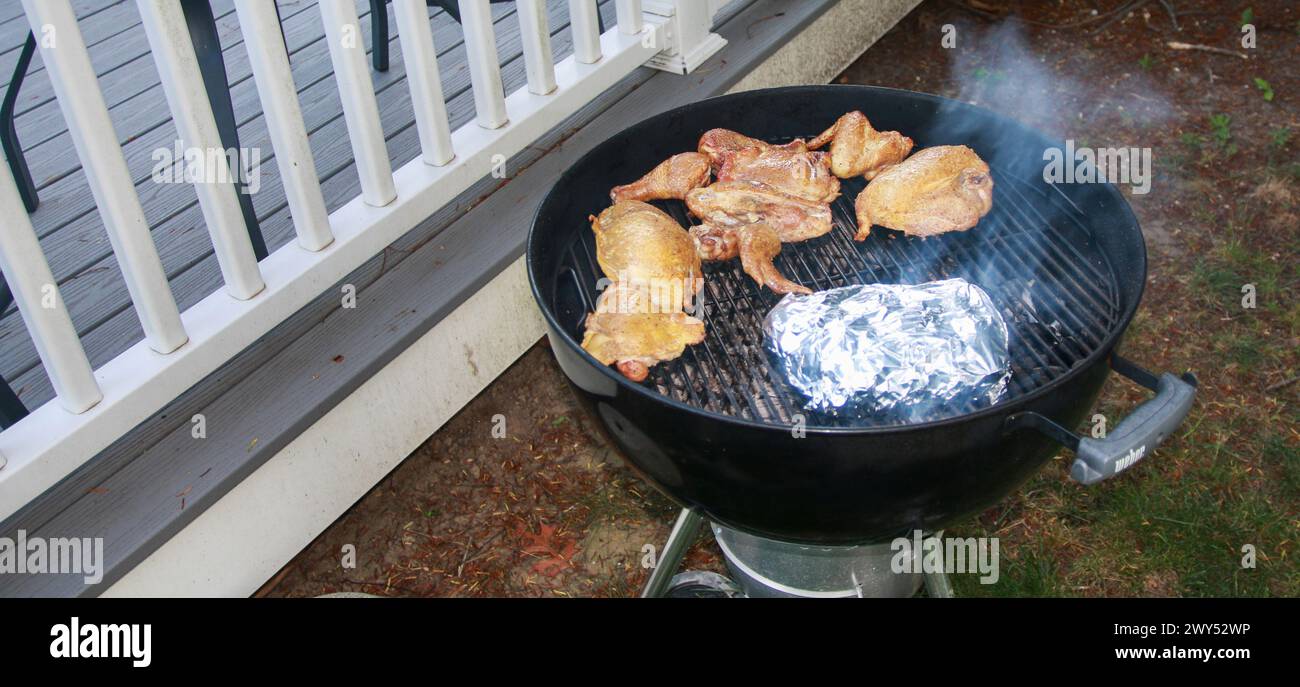 Una griglia barbecue con pezzi di pollo crudi cucinati sopra. Le grigliate creano segni di grigliatura sul pollo mentre cuoce alla perfezione. Foto Stock