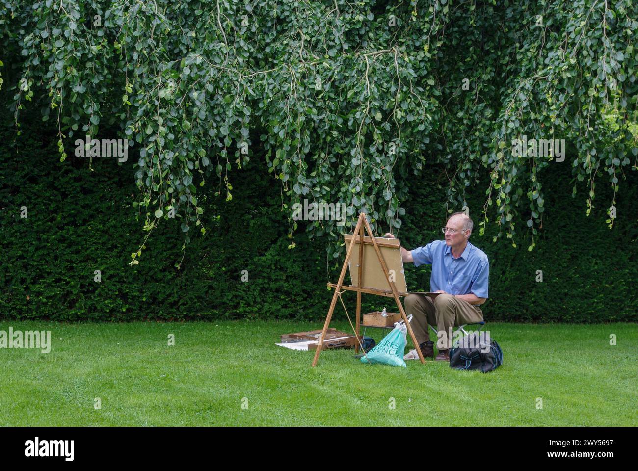 Artista maschile che lavora su un dipinto ad acquerello nei giardini di Cottesbrooke Hall, Northamptonshire, Regno Unito Foto Stock