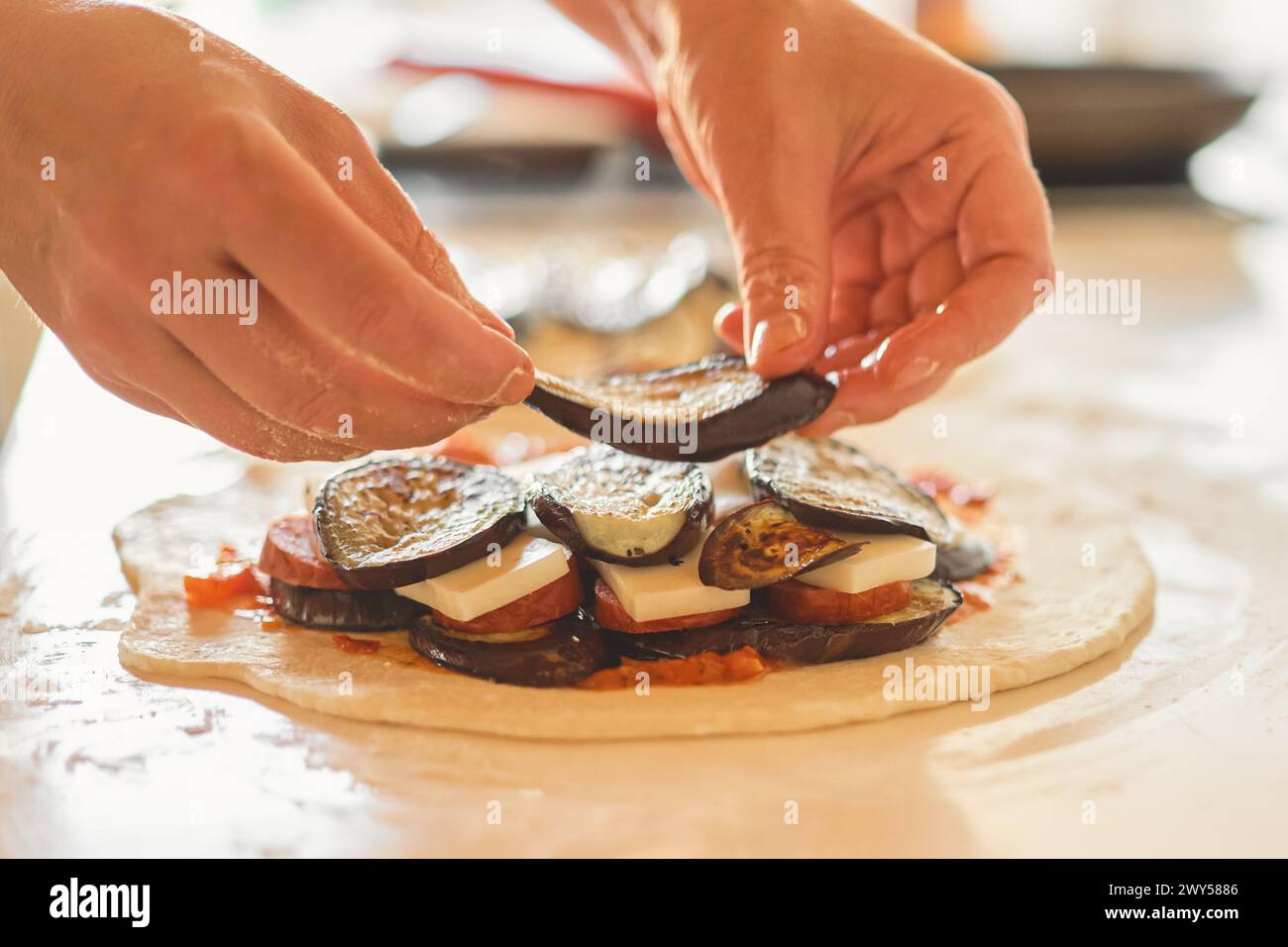 Lo chef piega gli ingredienti sull'impasto mentre prepara il tradizionale piatto italiano calzone, focalizzazione selettiva e sfondo sfocato Foto Stock