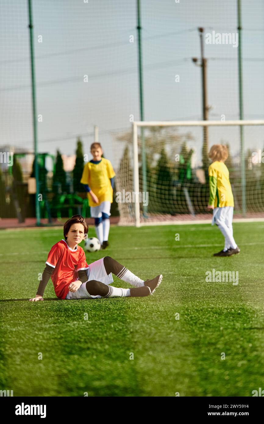 Un gruppo di bambini entusiasti sta giocando una vivace partita di calcio. Corrono, dribbling, passano e calciano la palla su una fiala erbosa Foto Stock