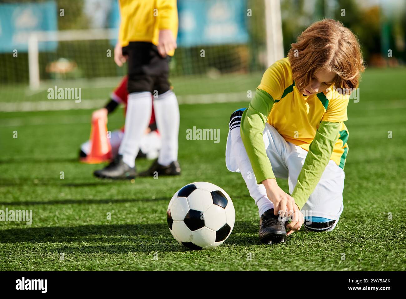 Una bambina con i pigtail gioca con una palla da calcio in un campo verde vivace, calciando, dribbling e esercitando le sue abilità. Foto Stock