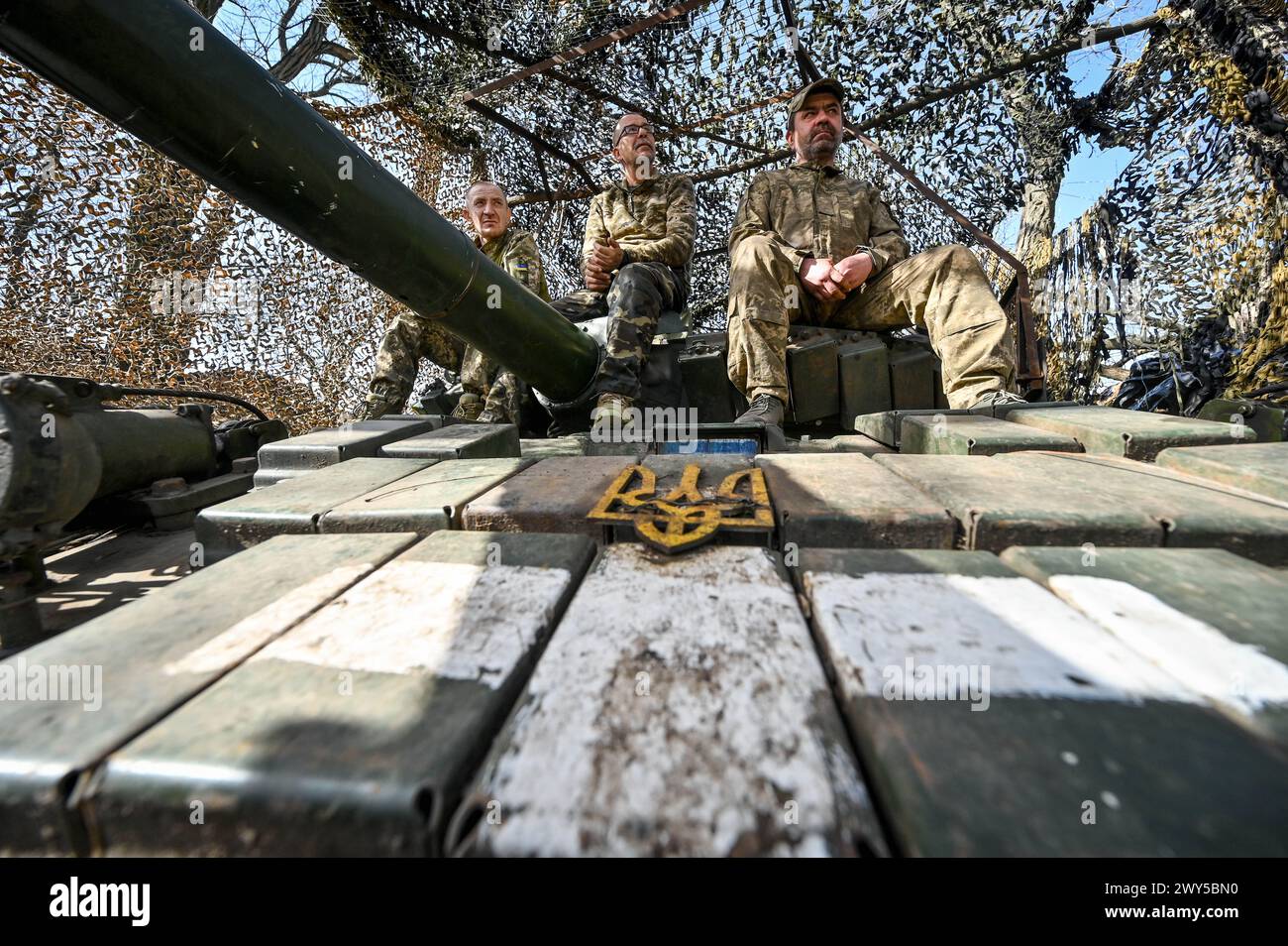 UCRAINA - 31 MARZO 2024 - tre soldati siedono su un carro armato della 1a Brigata carri armati delle forze terrestri ucraine, Ucraina. Foto Stock