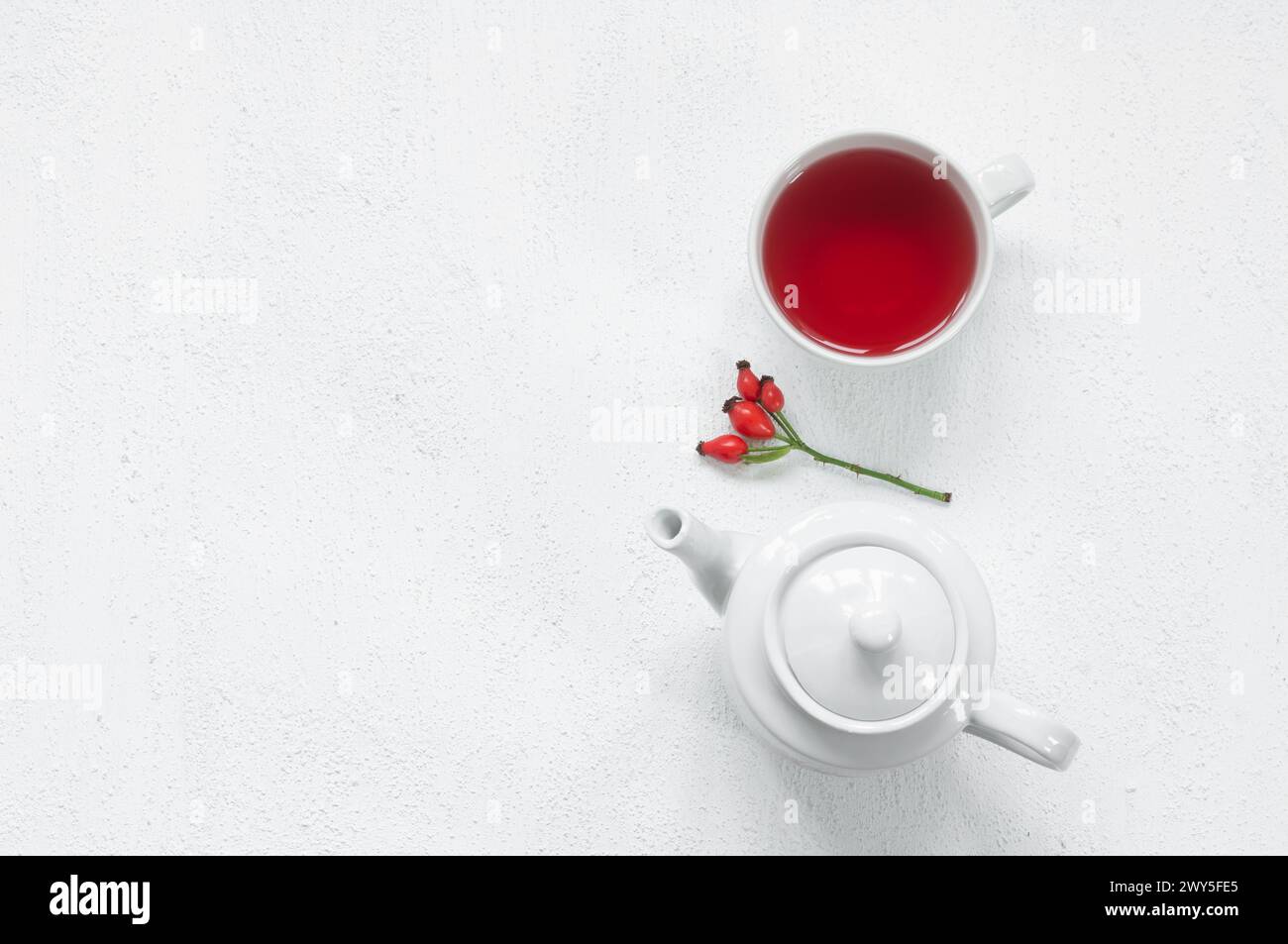 Tazza di vetro Rosehip di piante medicinali a base di tè a base di erbe con frutti di rosehip su tavola rustica. Tè invernale dogrose Foto Stock