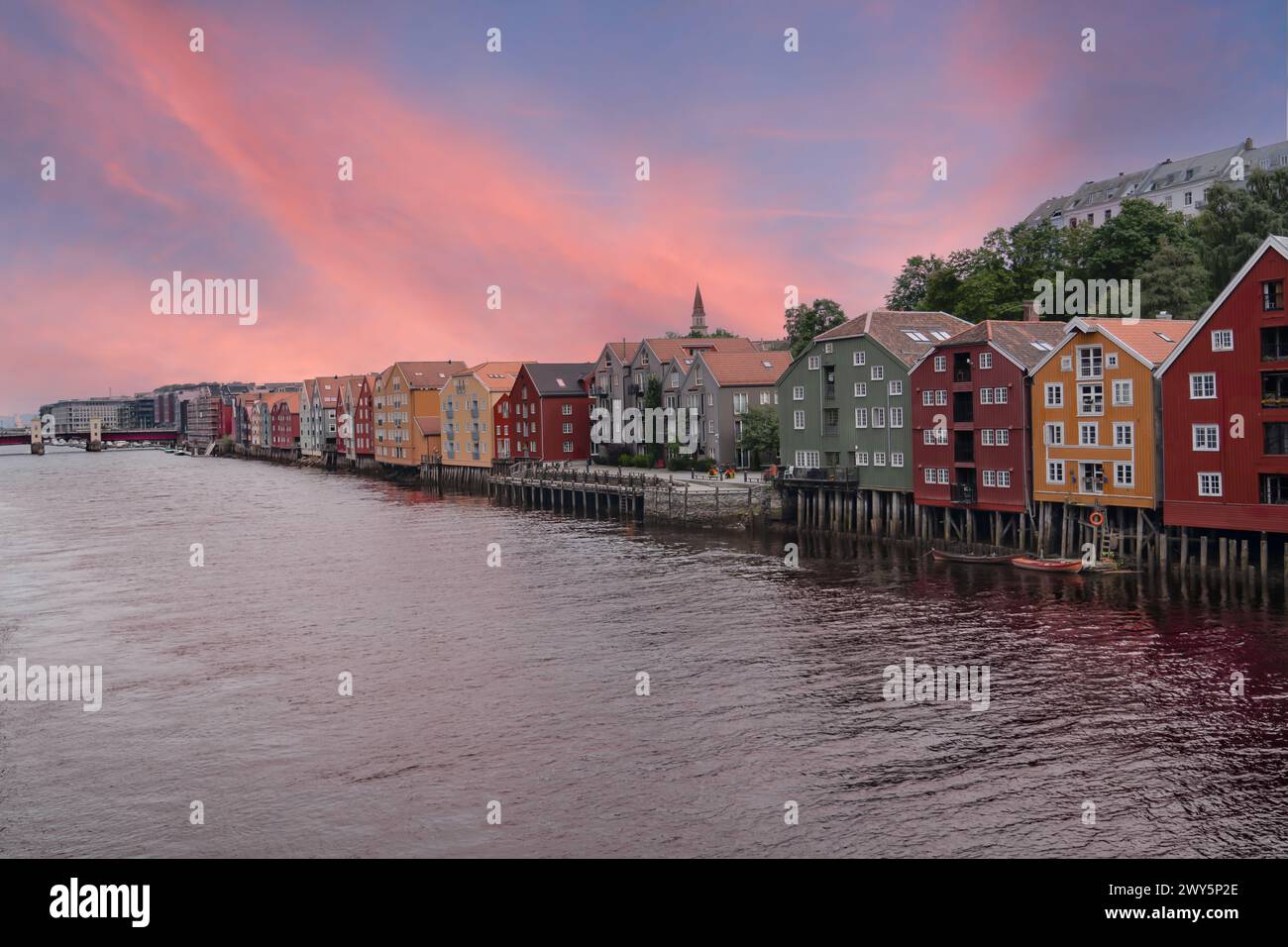 Cielo pastello al tramonto sulle case di Stilt nel quartiere di Brygge, lungo il fiume Nidelva a Trondheim, Norvegia. Destinazione di viaggio norvegese Foto Stock