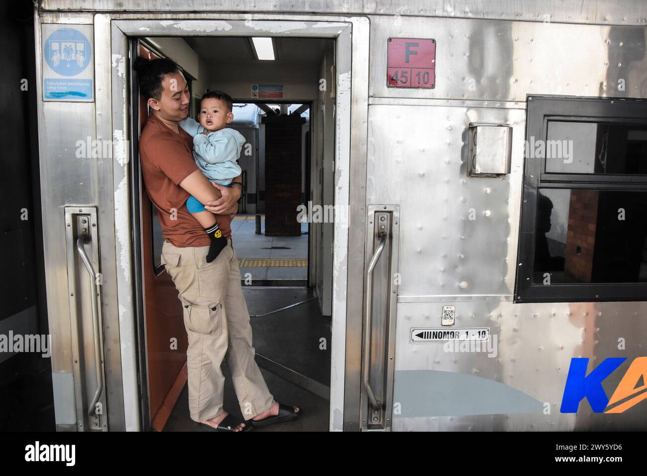 I passeggeri che tengono in braccio i propri figli mentre aspettano che il treno partisca al cancello del treno in vista della celebrazione Idul Fitri 1445 Hijriah alla stazione ferroviaria di Kiaracondong, Bandung, Giava Occidentale, Indonesia, il 4 marzo 2024. Milioni di persone stanno iniziando a partire per tornare nelle loro città natale. La tradizione di tornare a casa (mudik), che viene solitamente praticata dai musulmani indonesiani prima di Eid al-Fitr, è diventata ormai una parte importante della cultura e anche le persone approfittano di questo momento di ritorno a casa per riunirsi con i parenti nella loro città natale. (Foto di Dimas Rachmatsyah/Sipa USA) Foto Stock