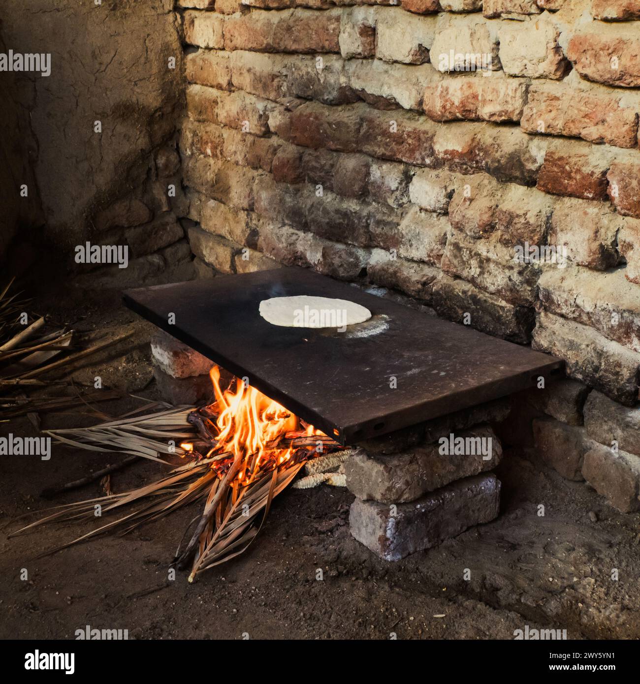 Pane piatto egiziano cucinato su fornelli a vista nella zona cucina all'aperto di un contadino Foto Stock