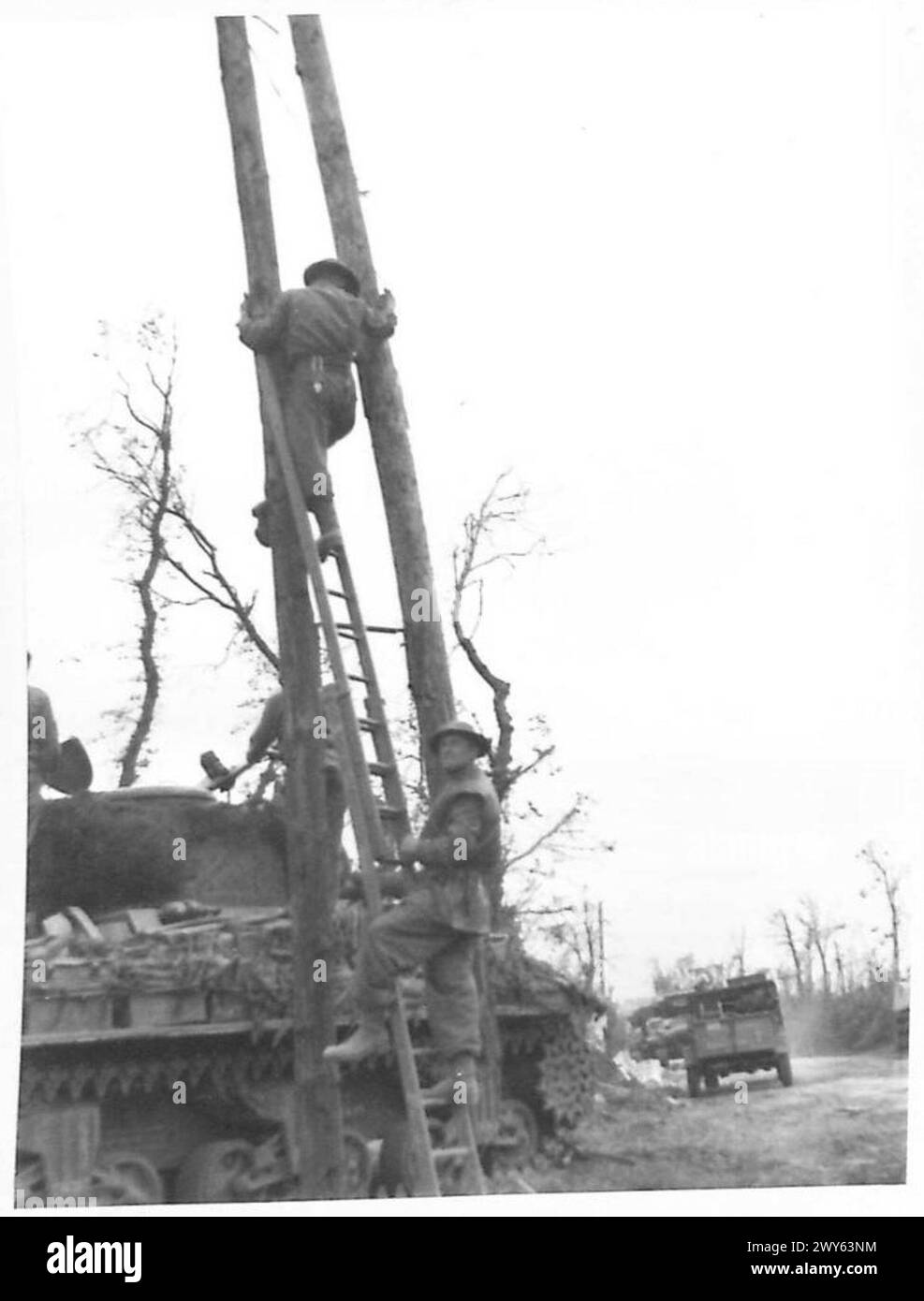 Durante l'attacco a Caen, i segnali della Divisione 59 del Royal Corps of Signals seguono la fanteria in un villaggio a nord di Caen per installare e riparare i cavi telefonici da campo. Parte dell'esercito britannico, operazioni del 21st Army Group. Foto Stock