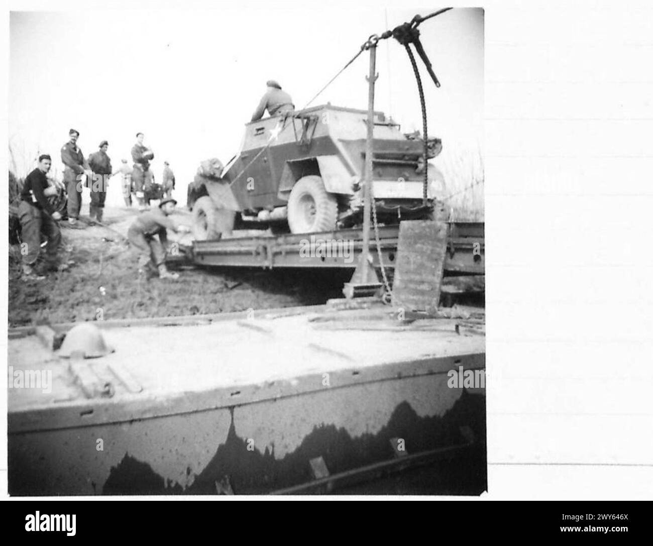 Un'auto da ricognizione parte da una zattera affondata utilizzata nell'attraversamento del Reno, procedendo in Germania come parte delle operazioni dell'esercito britannico, 21st Army Group. Foto Stock