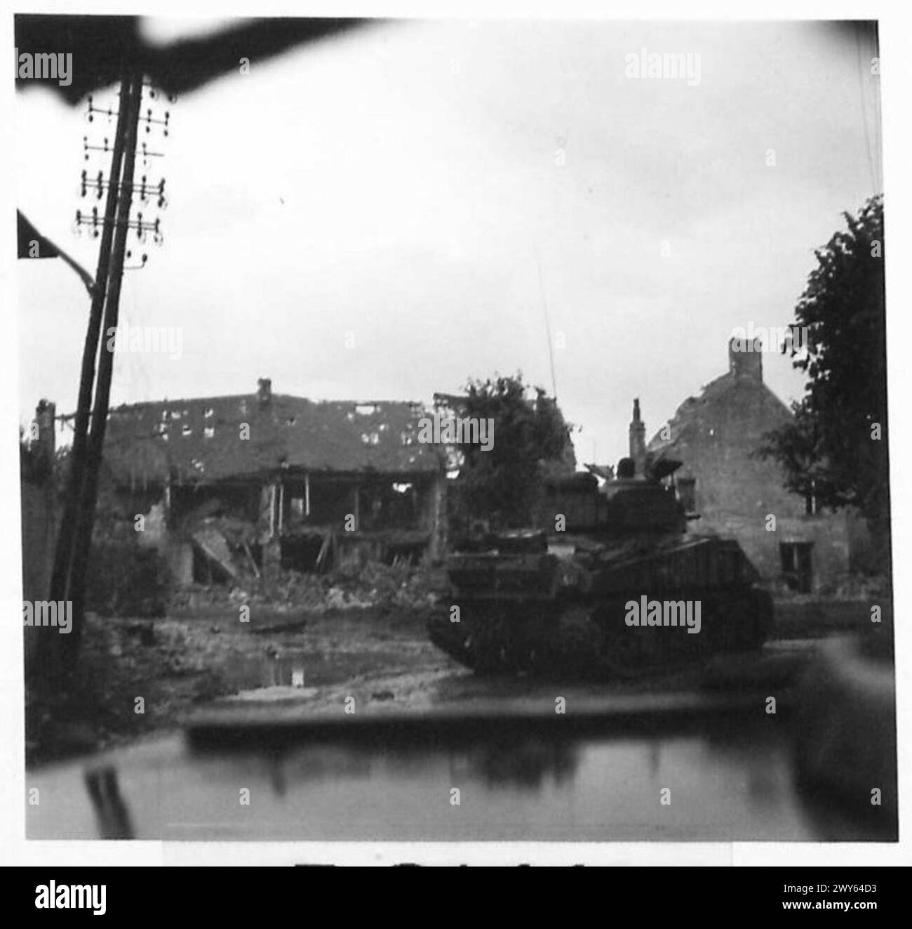 Un carro Sherman avanzò attraverso Cheux durante l'offensiva britannica in Normandia, registrata dall'esercito britannico, 21st Army Group. Foto Stock