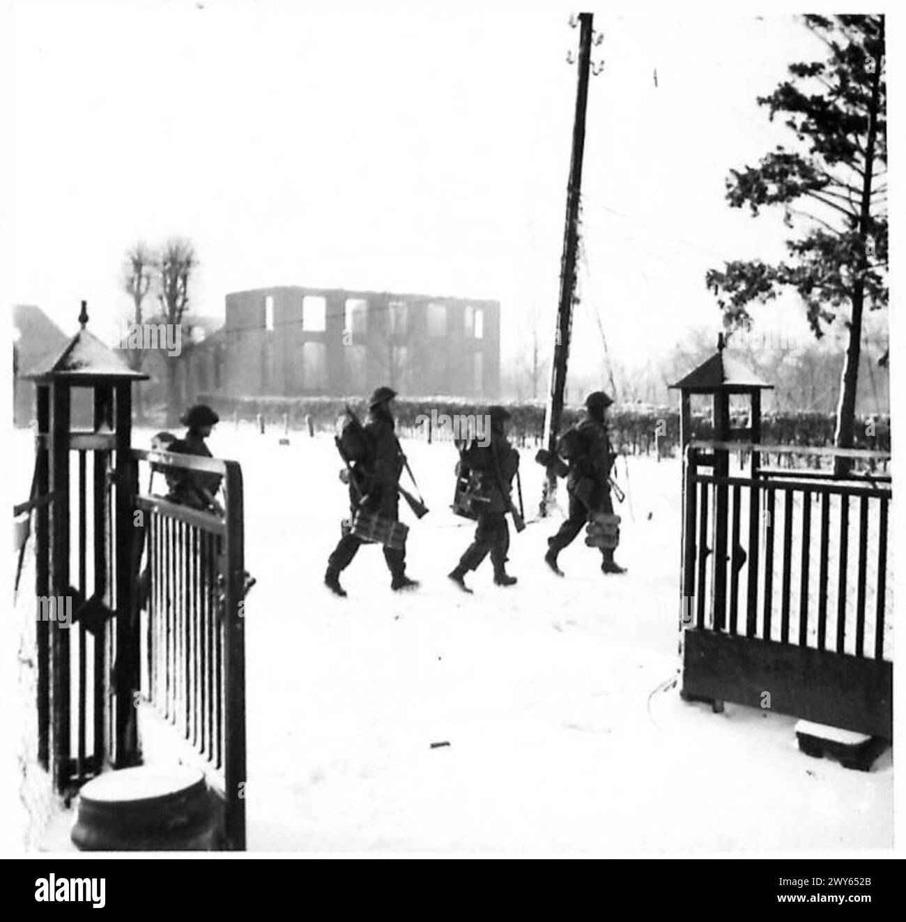 La fanteria del 2nd Battalion Essex Regiment avanzerà lungo strade innevate verso Zetten con un edificio in fiamme sullo sfondo, illustrando le operazioni di combattimento in prima linea, British Army, 21st Army Group. Foto Stock