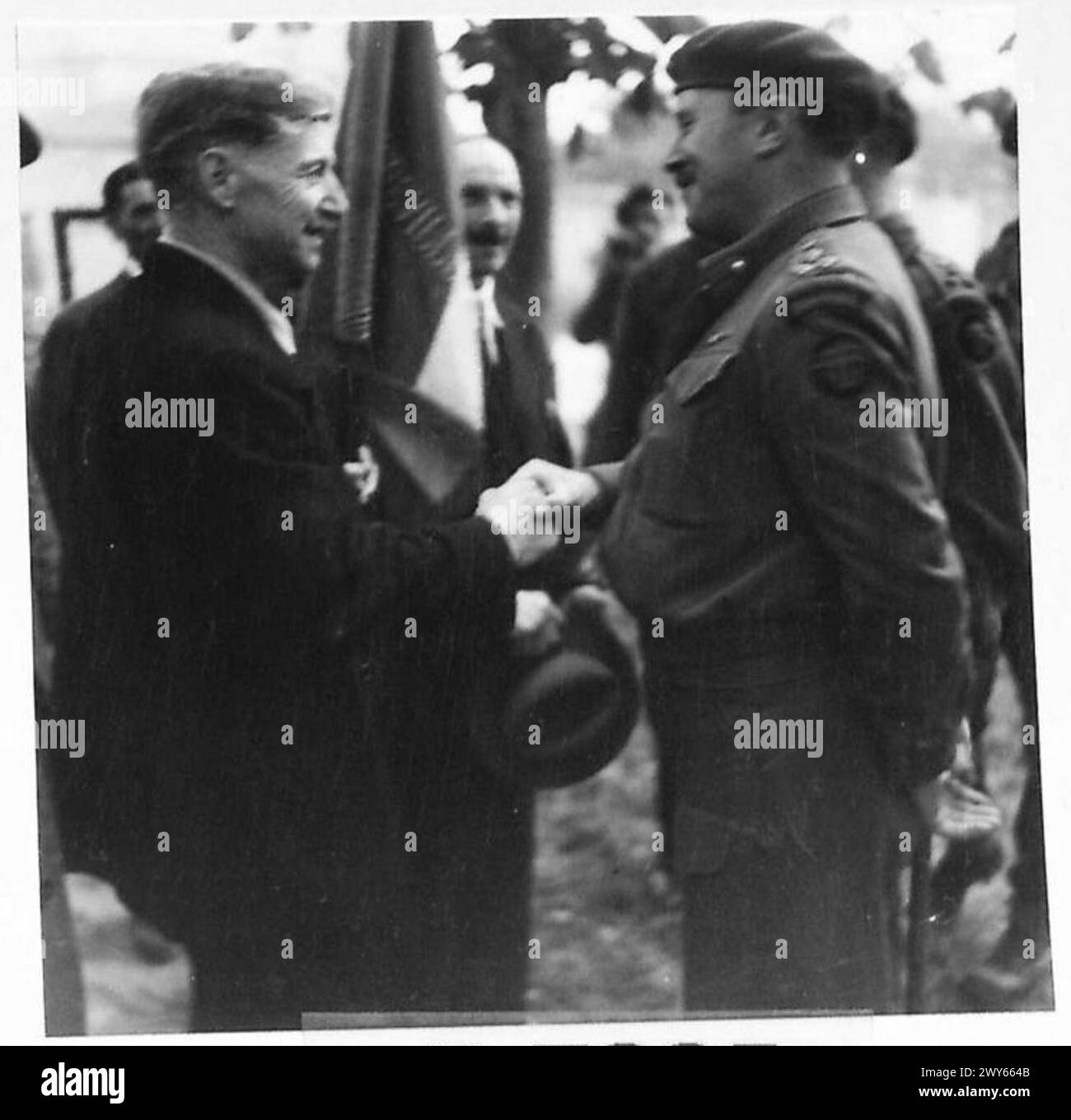 Il brigadiere J. Slater dell'esercito britannico saluta un membro della Amfreville Old Comrades Association nel giorno della Bastiglia in Normandia, con il portatore di bandiera M. Isadore Larus presente. Foto Stock