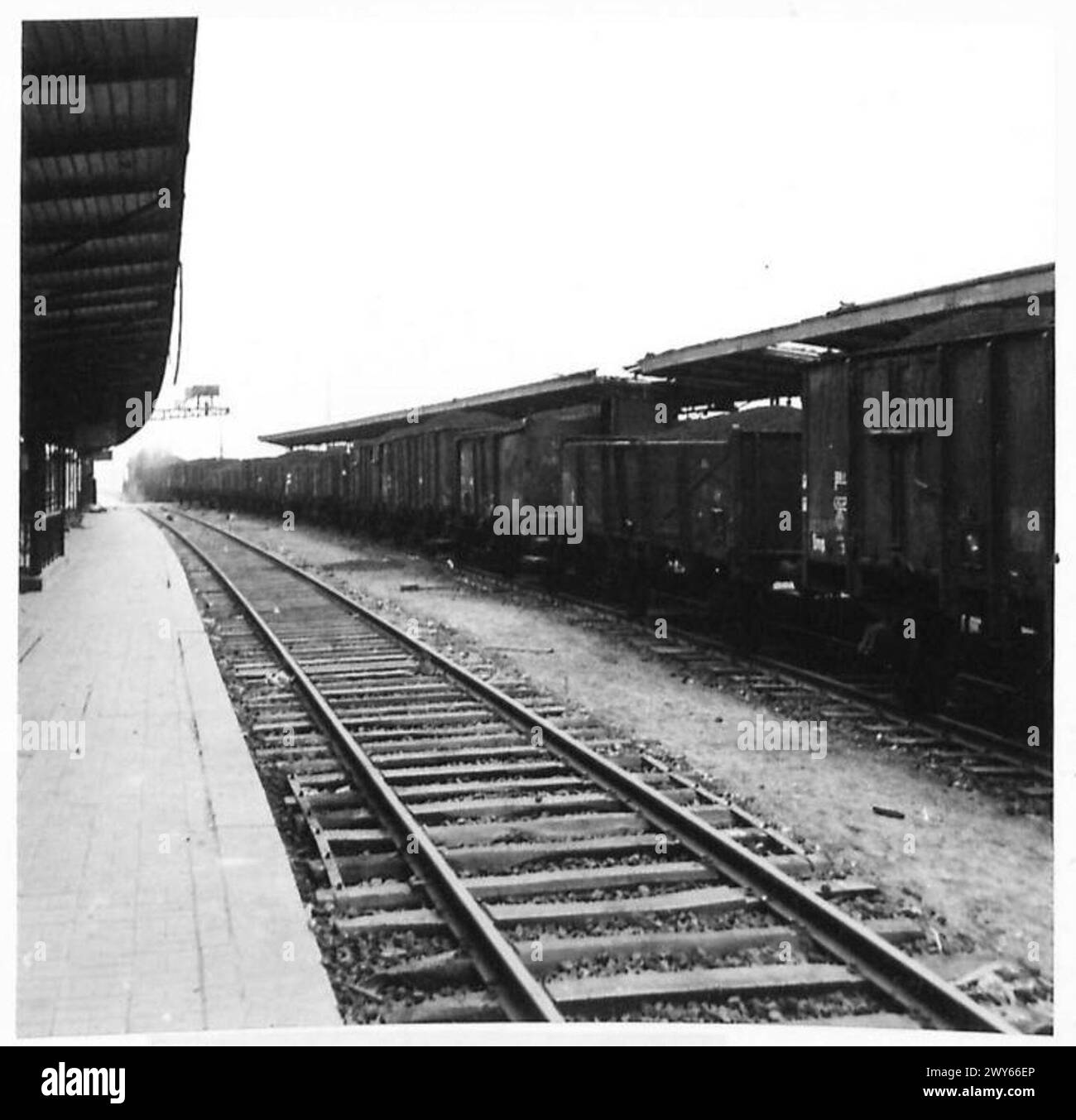 Un motore diesel-elettrico americano tira un treno merci di 25 camion caricati con zavorra lungo la linea ferroviaria Caen-Cherbourg, illustrando la ricostruzione ferroviaria, le operazioni logistiche alleate e la collaborazione tra ingegneri britannici e americani e dipendenti civili francesi, 1944. Foto Stock