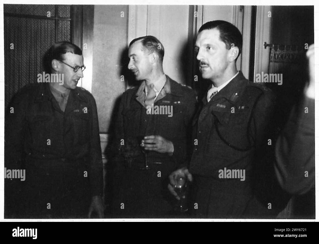 Durante una cena formale ad Alamein, sono presenti il brigadiere E.T. Williams, il tenente colonnello L.M. Murphy e il brigadiere R.F.K. Belchem del 21st Army Group dell'esercito britannico, che riflette la tradizione militare e cameratista. Foto Stock