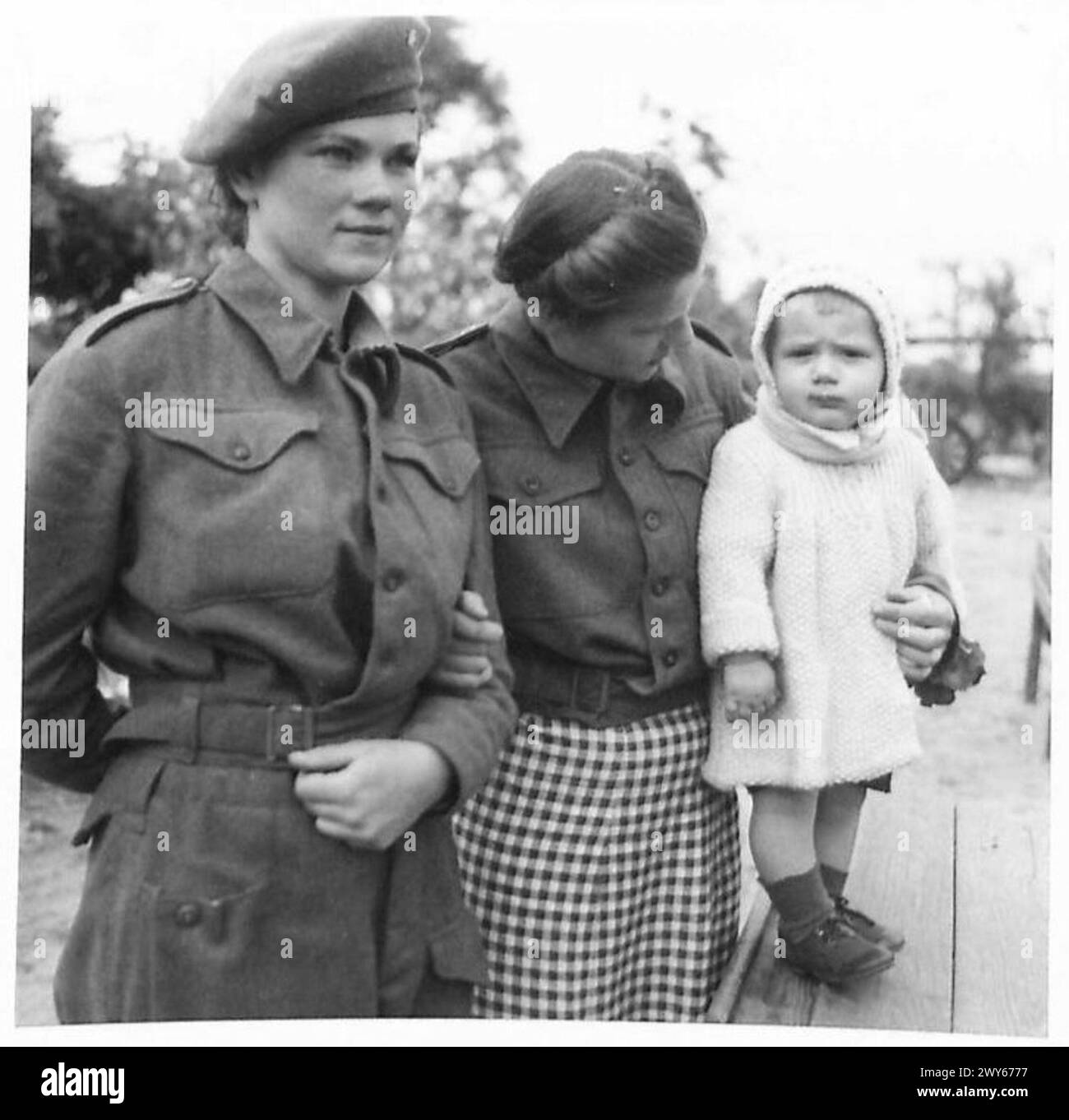 Due infermiere russe osservano un concerto con un bambino in un campo di sfollati sotto la supervisione del 21st Army Group dell'esercito britannico. Foto Stock