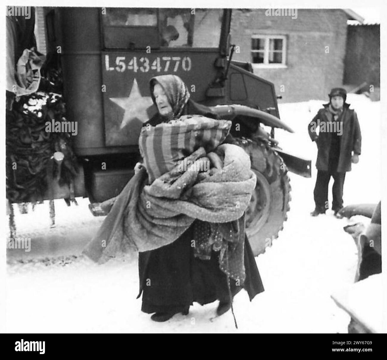 Un'anziana donna tedesca trasporta oggetti personali da un camion da 3 tonnellate alla sua nuova casa a Tuddern, riflettendo lo spostamento civile e il recupero nell'area del Triangolo di Sittard durante le operazioni alleate, British Army, 21st Army Group. Foto Stock