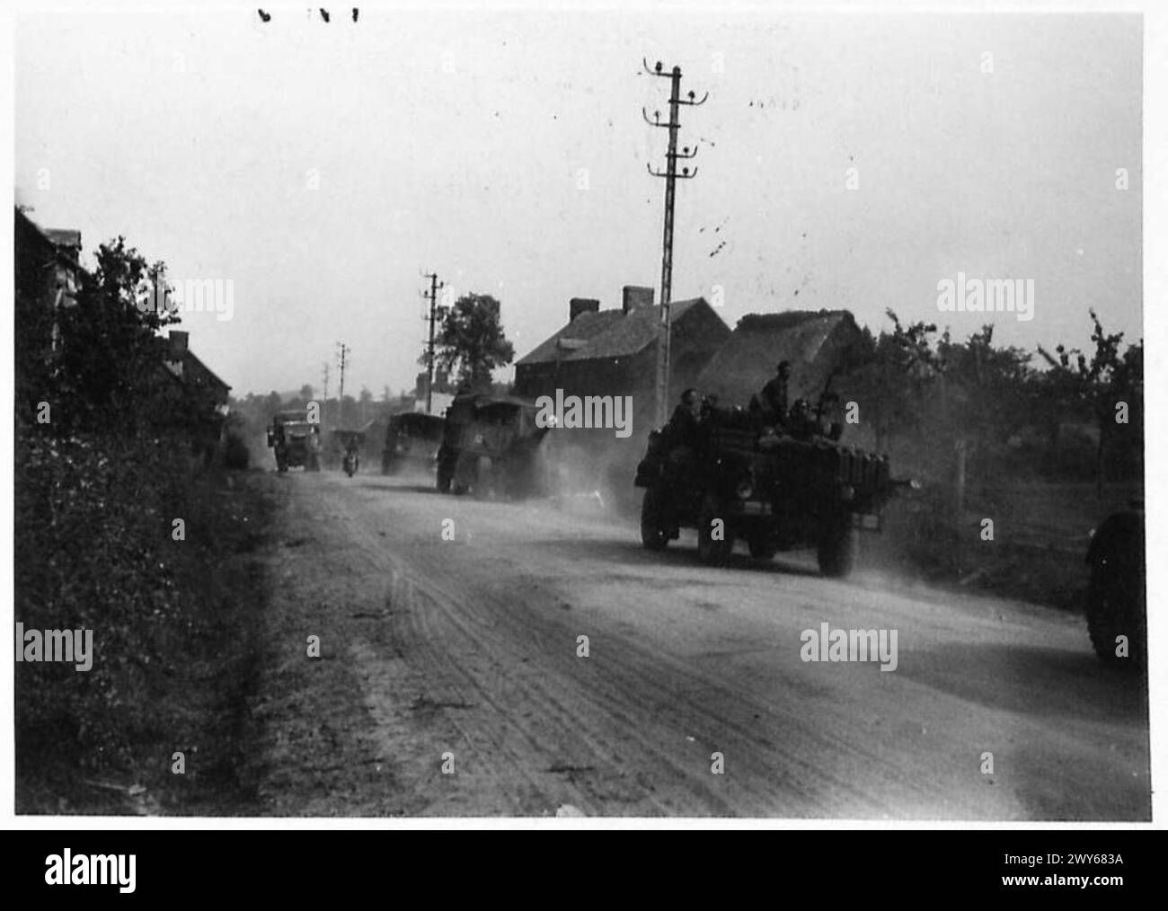 CON LE FORZE BRITANNICHE IN NORMANDIA - cannoni e attrezzature inglesi che passano attraverso il villaggio distrutto di Vallee. , British Army, 21st Army Group Foto Stock