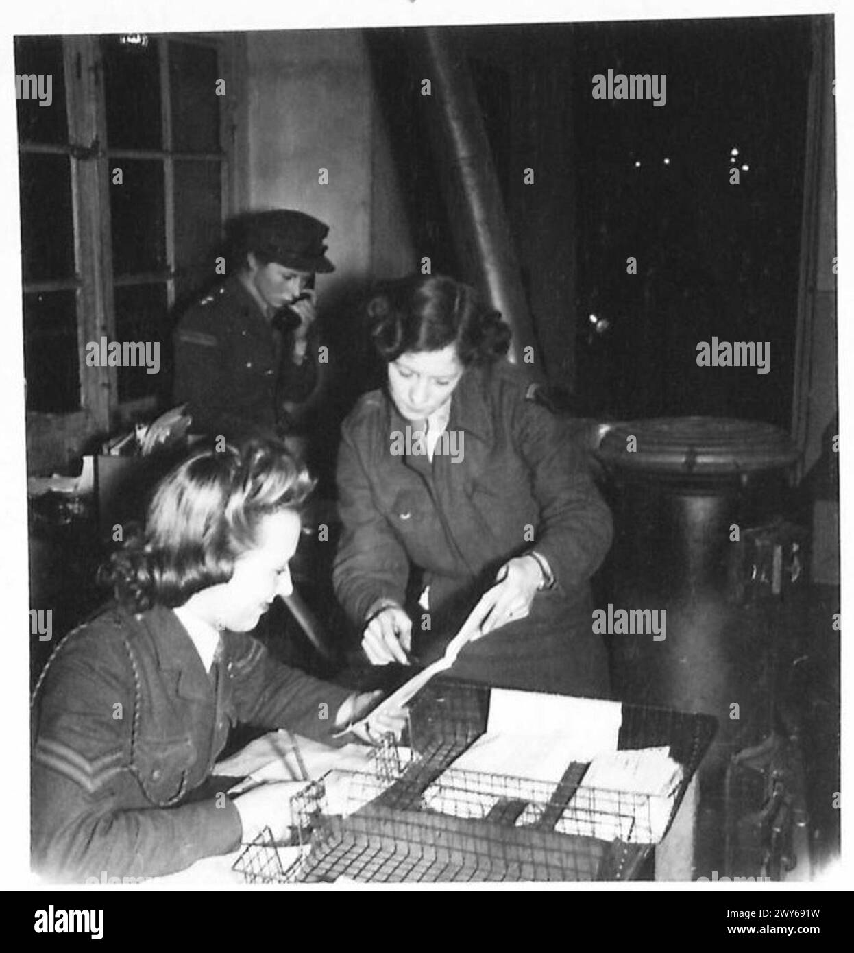 RAGAZZE DI SERVIZIO dello S.H.A.E.F. - al banco di circolazione nell'ufficio telestampatore. [A sinistra] Cpl. E. McNeil di Wallasey, Cheshire. È in A.T.S. dal novembre 1939. Sta ricevendo un messaggio di telestampa da Pte. Beatrice Hayward di Ardwick, Manchester. , British Army, 21st Army Group Foto Stock